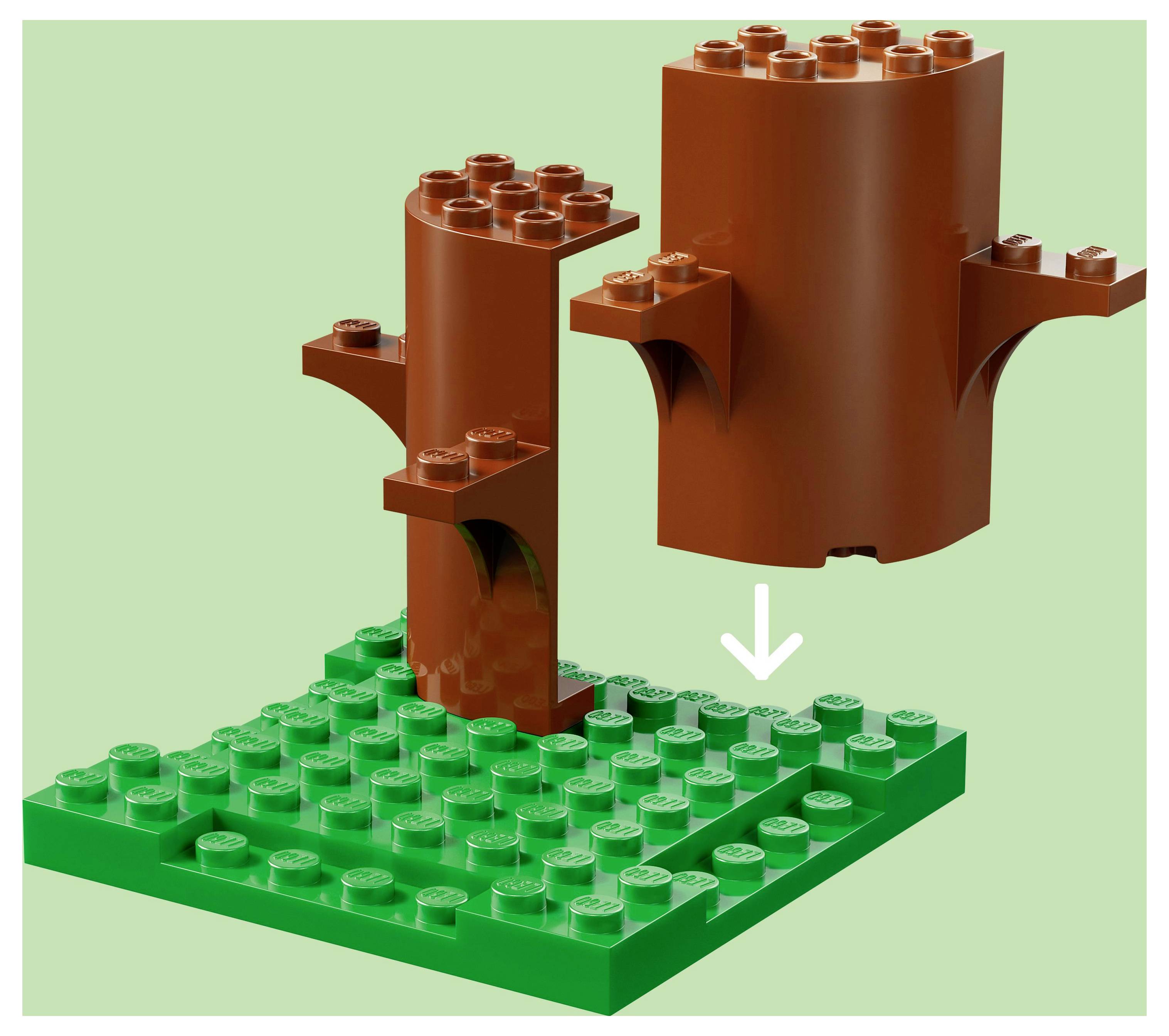 Ein brauner, baumförmiger Legostein wird auf eine grüne Legogrundplatte gelegt, wobei ein Pfeil die Platzierung anzeigt.