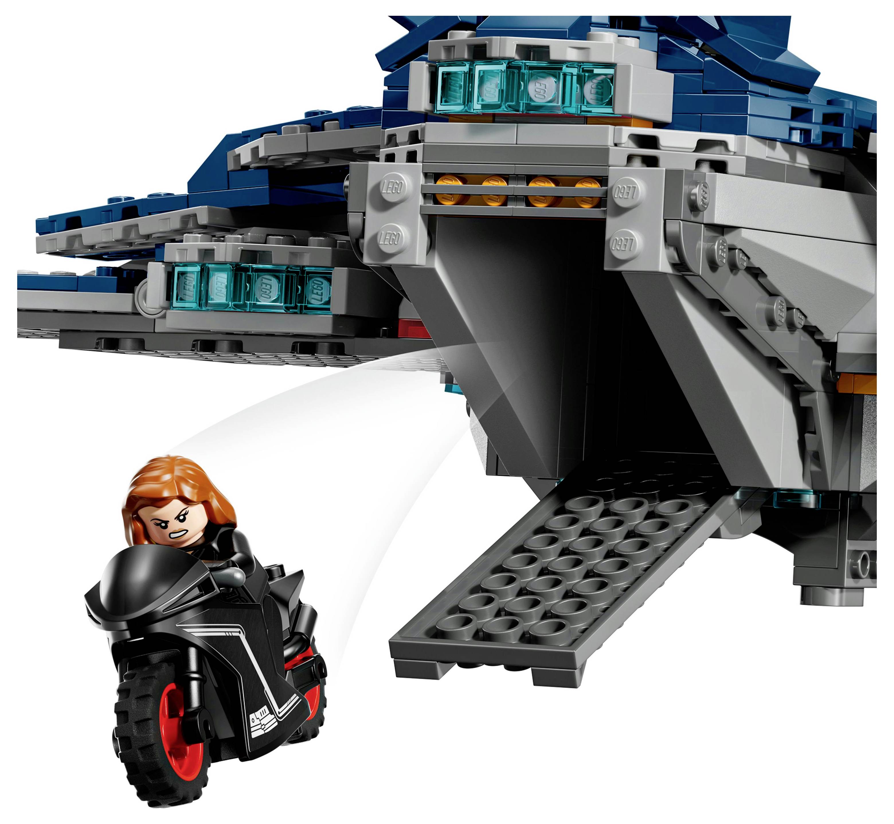 Eine Spielzeugfigur auf einem schwarzen Motorrad verlässt ein Raumschiff mit blauen Akzenten über eine ausgefahrene Rampe.