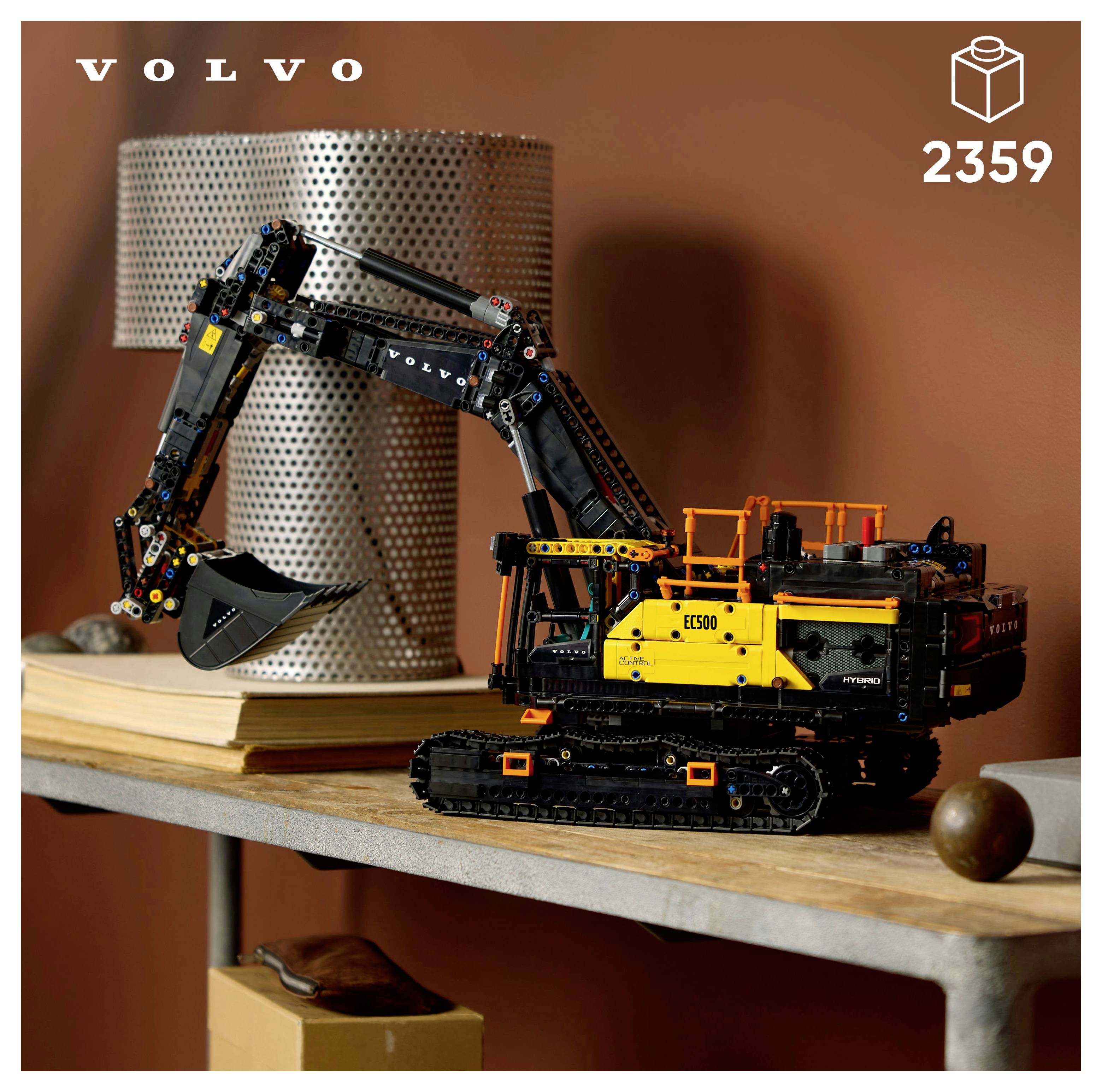 Modell eines Volvo-Baggers, aufgebaut aus LEGO-Teilen, steht auf einem Tisch neben einem zylindrischen Metallbehälter und einigen Dekorationselementen.