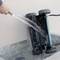 Ein Staubsaugerroboter wird mit Wasser gereinigt, während er kopfüber liegt. Eine Hand hält den Wasserschlauch.