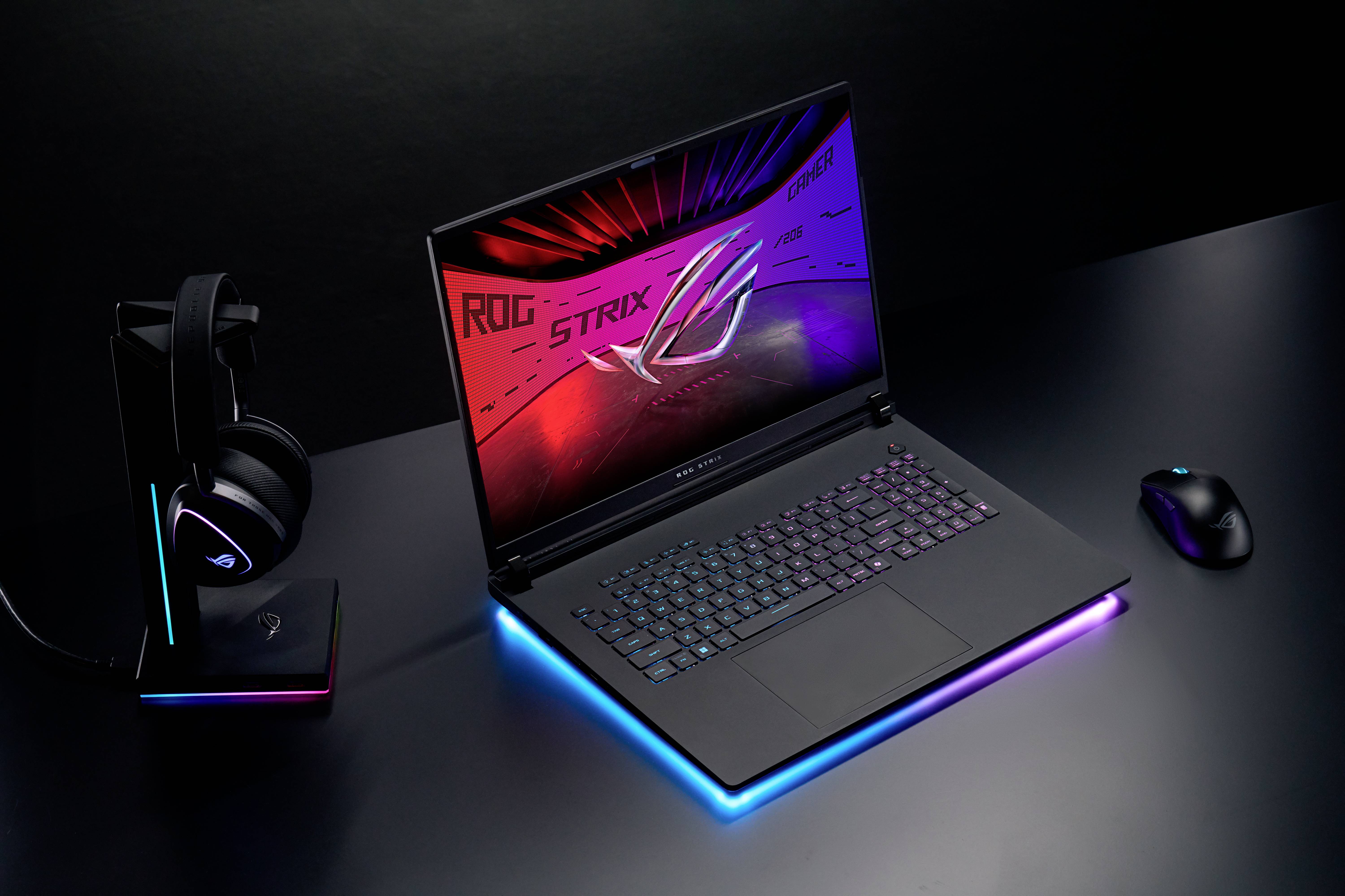 Ein Gaming-Laptop auf einem Tisch, umgeben von einer Maus und einem Headset, mit leuchtenden RGB-Details und einem markanten Bildschirm.