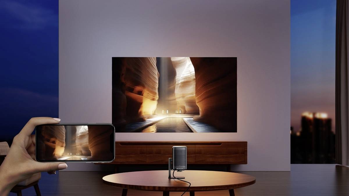 Hand hält Smartphone mit Bild von Antelope Canyon. Im Hintergrund ein großer Fernseher zeigt das gleiche Bild. Wohnzimmer im modernen Stil.
