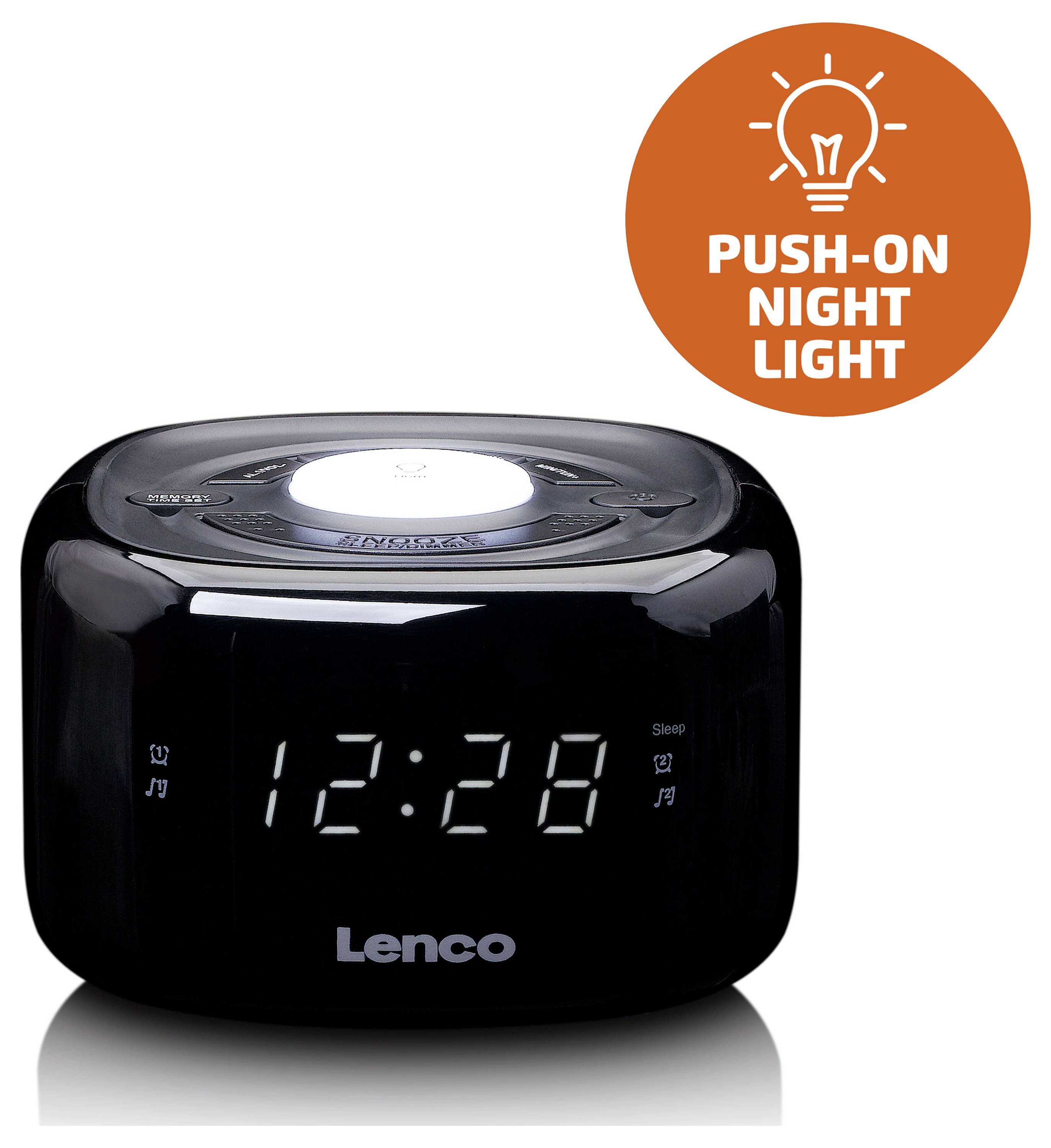 Ein schwarzer Wecker mit LED-Anzeige zeigt "12:28". Oben ist eine Nachtlicht-Funktion und ein orangefarbener Aufkleber mit 'Push-On Night Light'.
