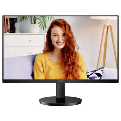 Monitor zeigt Frau mit roten Haaren in gelbem Pullover auf einem Sofa. Im Hintergrund Pflanzen und Lampe sichtbar.