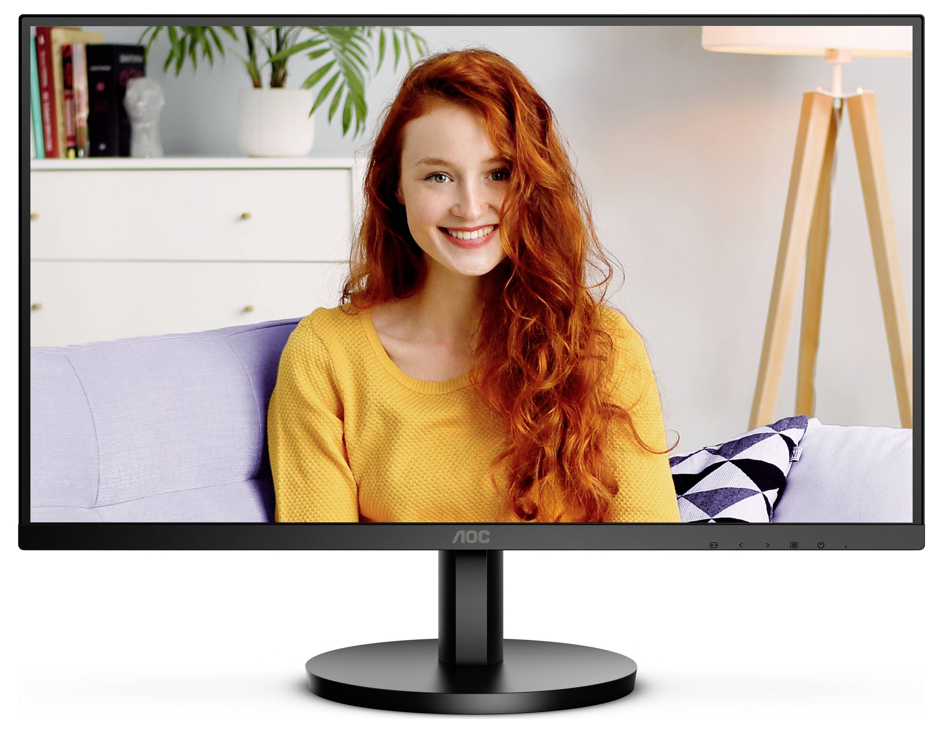 Eine lächelnde Person mit langen, roten Haaren sitzt auf einem Sofa; im Hintergrund sind eine Pflanze und eine Lampe zu sehen.