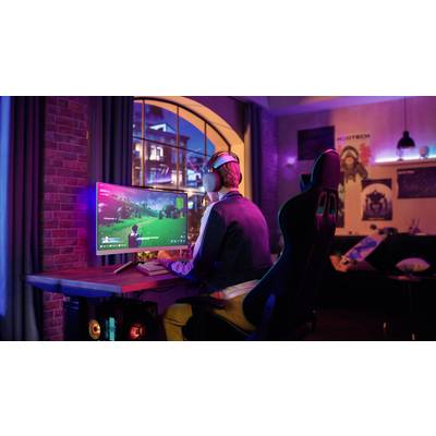 Eine Person spielt ein Videospiel am Computer in einem abgedunkelten Raum. Die Szene wirkt entspannend und konzentriert.