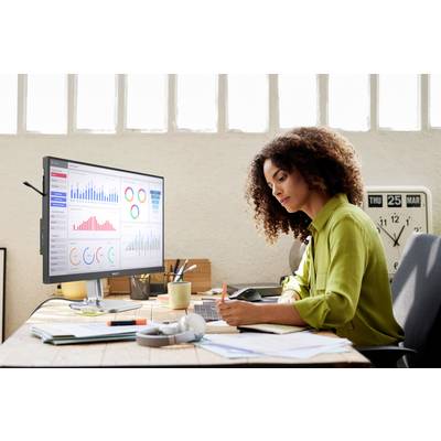 Frau arbeitet an einem Schreibtisch mit einem Computer, der verschiedene farbige Grafiken und Diagramme anzeigt.