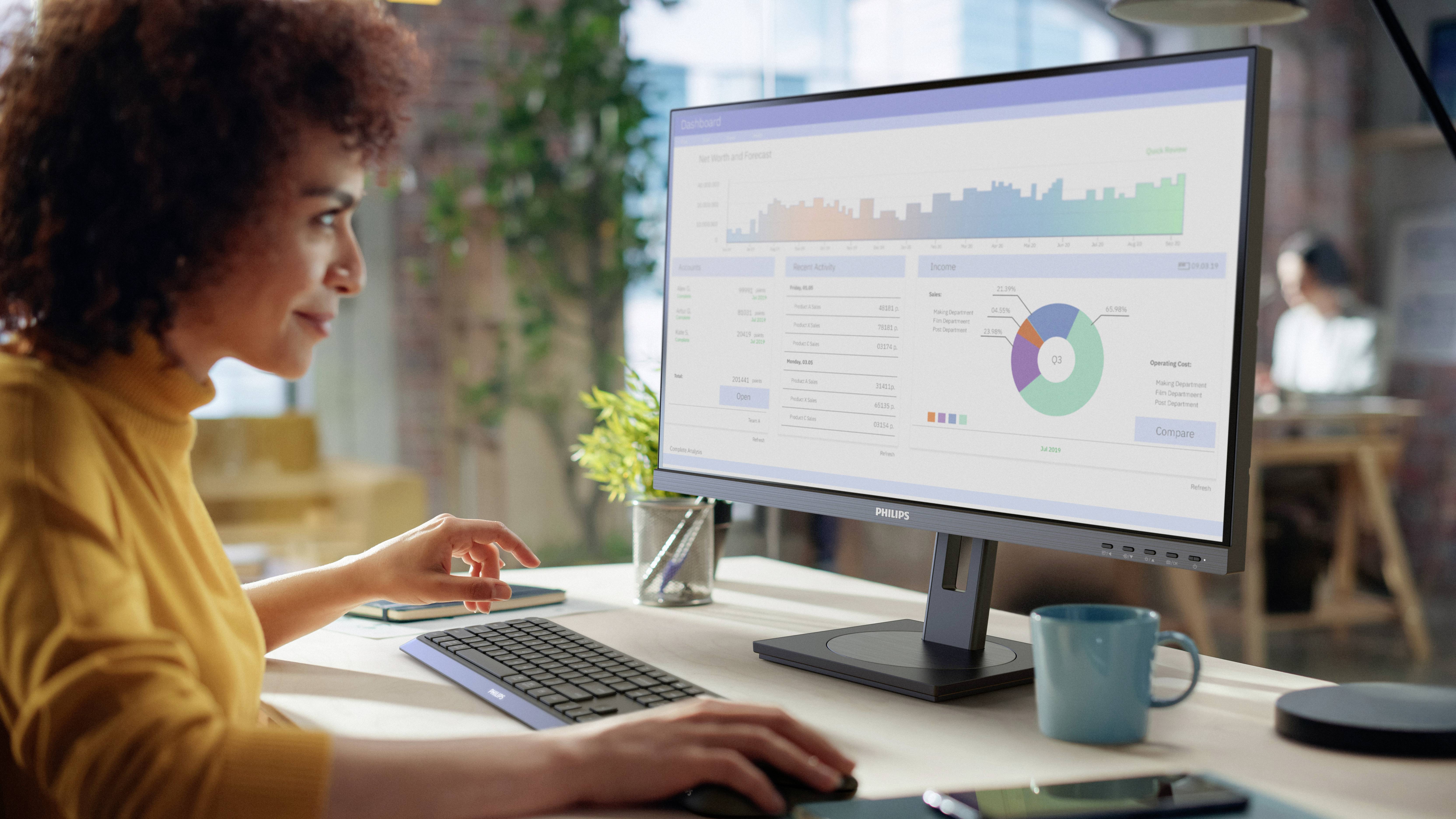 Eine Person betrachtet Daten auf einem Computerbildschirm, der Grafiken und Diagramme anzeigt. Im Hintergrund ist ein modernes Büro zu sehen.