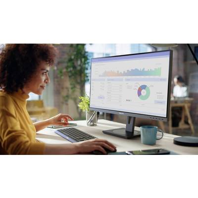 Eine Person betrachtet Daten auf einem Computerbildschirm, der Grafiken und Diagramme anzeigt. Im Hintergrund ist ein modernes Büro zu sehen.