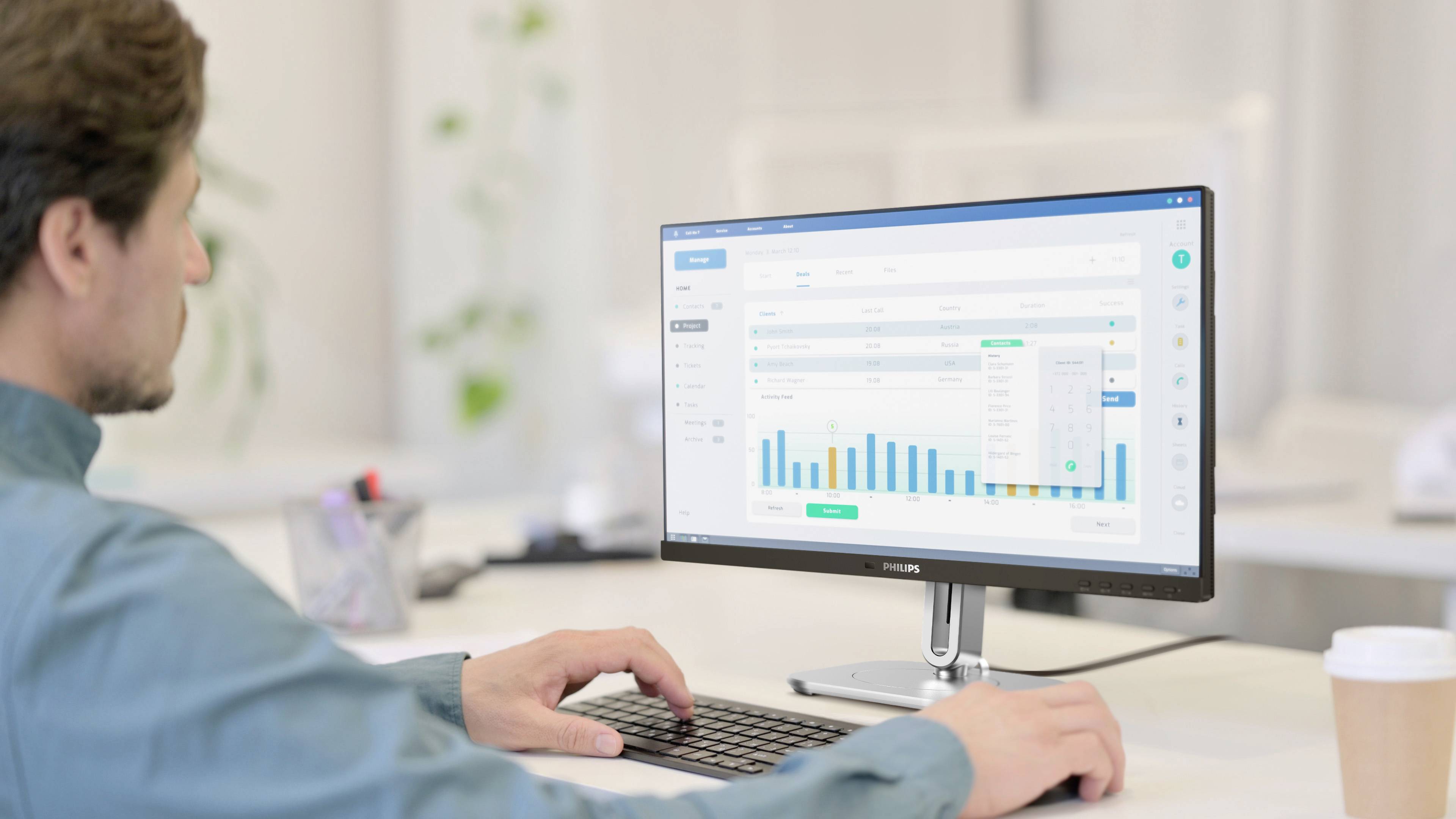 Ein Mann sitzt an einem Schreibtisch und arbeitet am Computer. Auf dem Bildschirm sind bunte Balkendiagramme und Tabellen zu sehen.