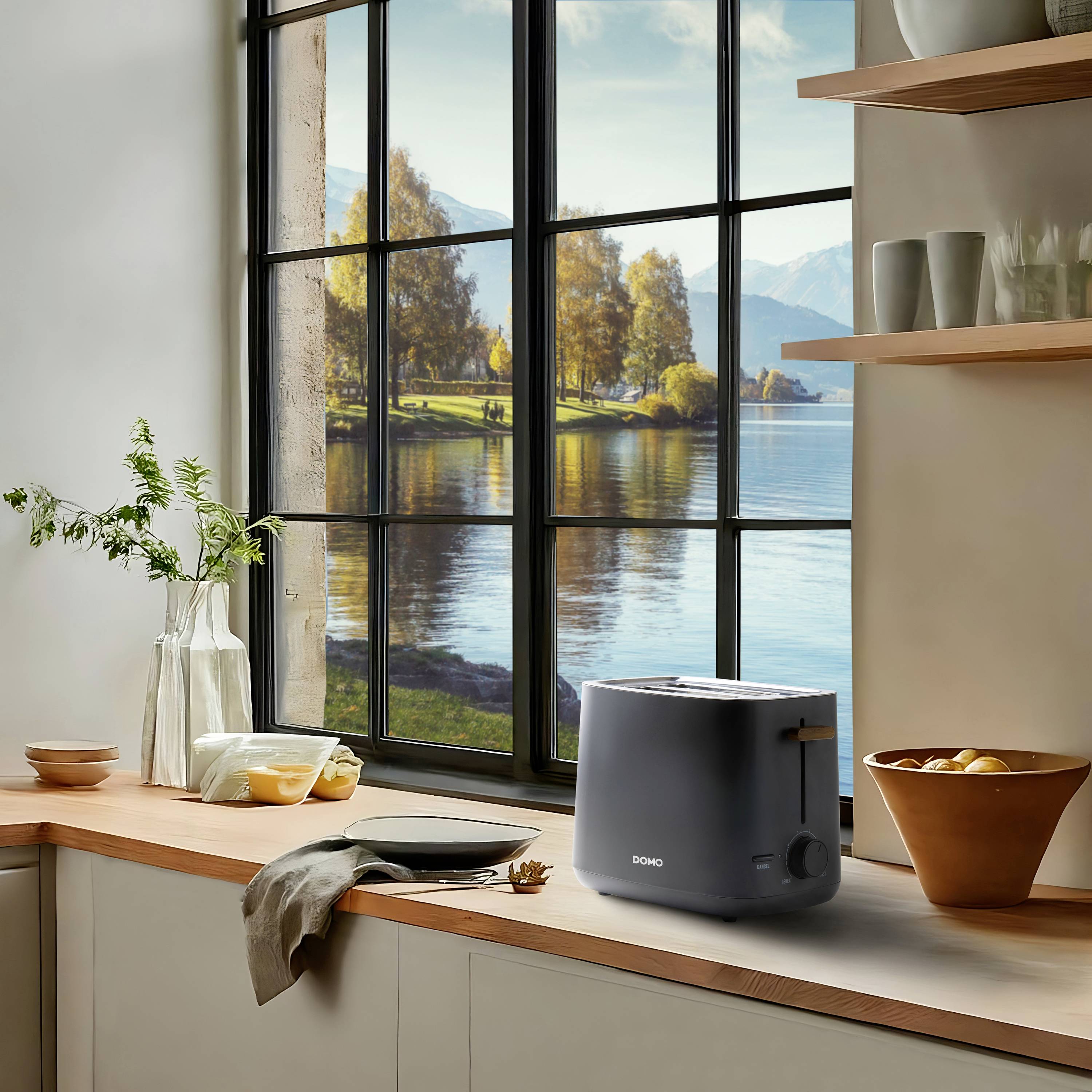 Küche mit großem Fenster, zeigt See und Bäume draußen; Toaster und Schalen auf Holzarbeitsplatte, dezente, warme Farbgebung.