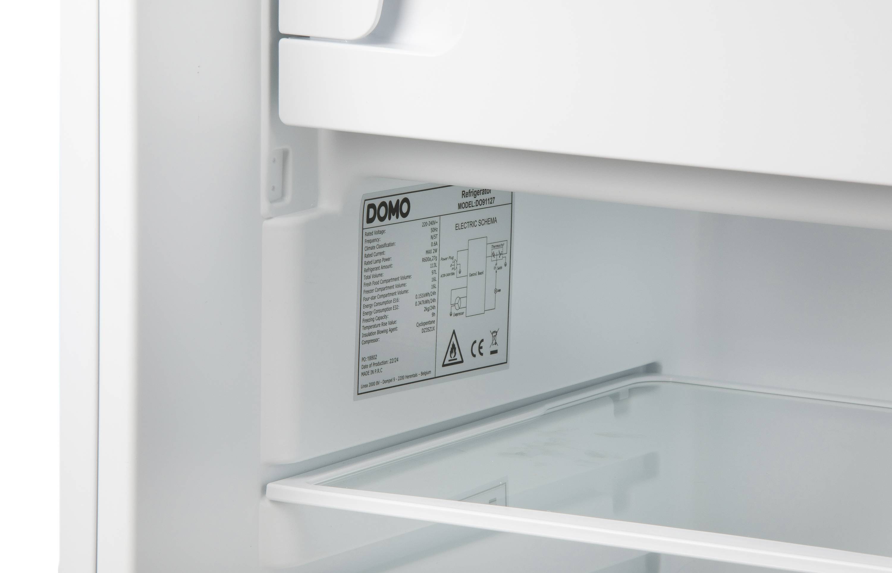 Ein offener Kühlschrank mit Etikett von 'DOMO' auf der Innenseite, zeigt Glasregale und technische Spezifikationen.