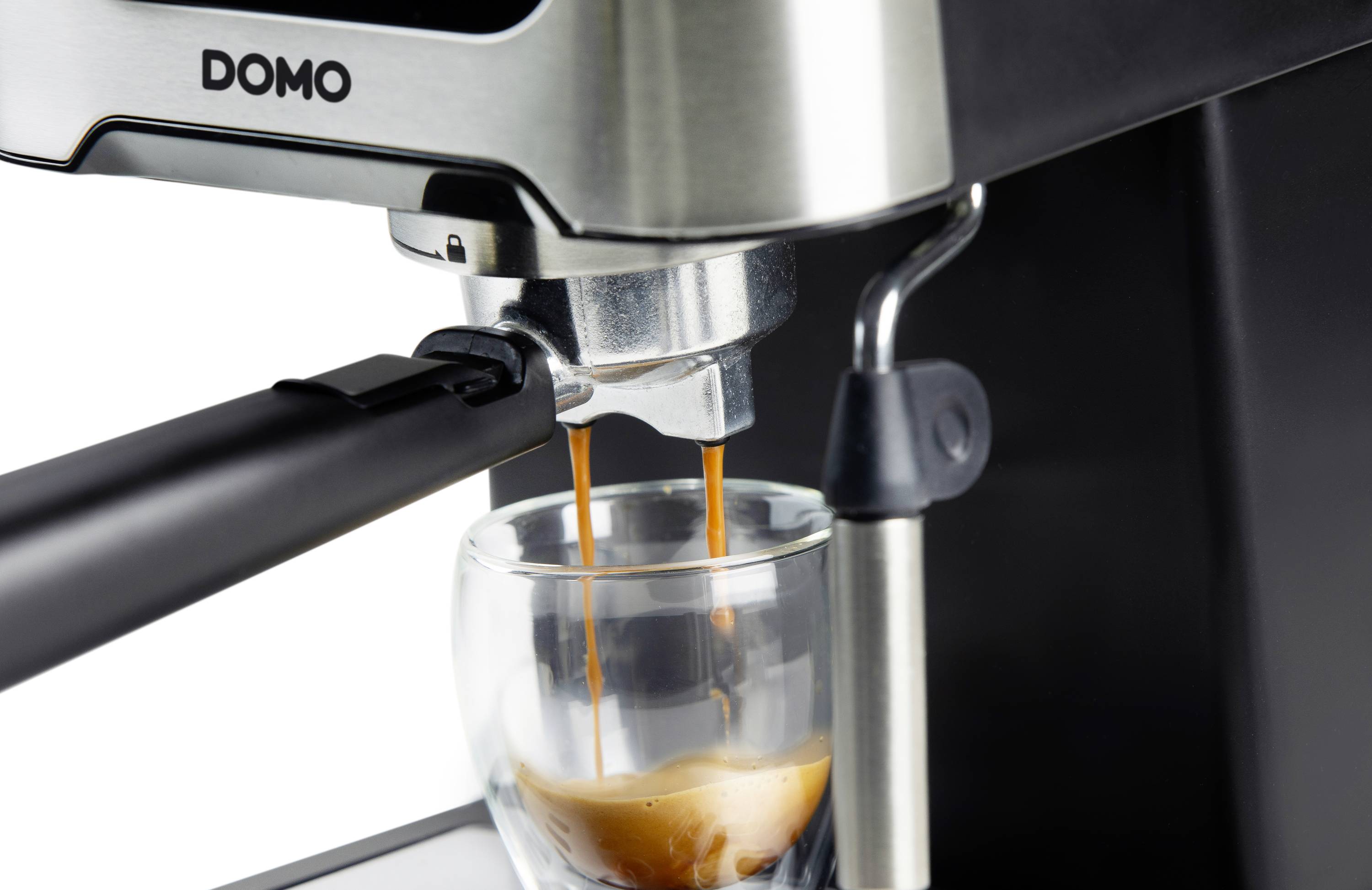 Espressomaschine brüht Kaffee in Glas. Dampf tritt aus, während die Maschine läuft.