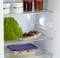 Ein geöffneter Kühlschrank mit Joghurt, Marmelade, Salat, Kirschkuchen und Bananen in einem Behälter.