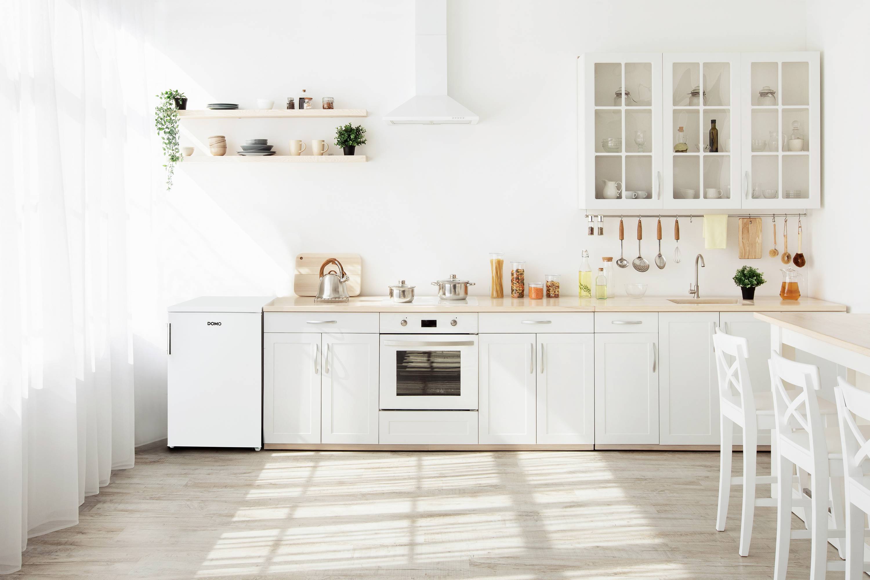 Moderne Küche mit weißen Schränken, Herd und Kühlschrank. Offene Regale und Hängeschränke mit Geschirr. Helles Tageslicht.