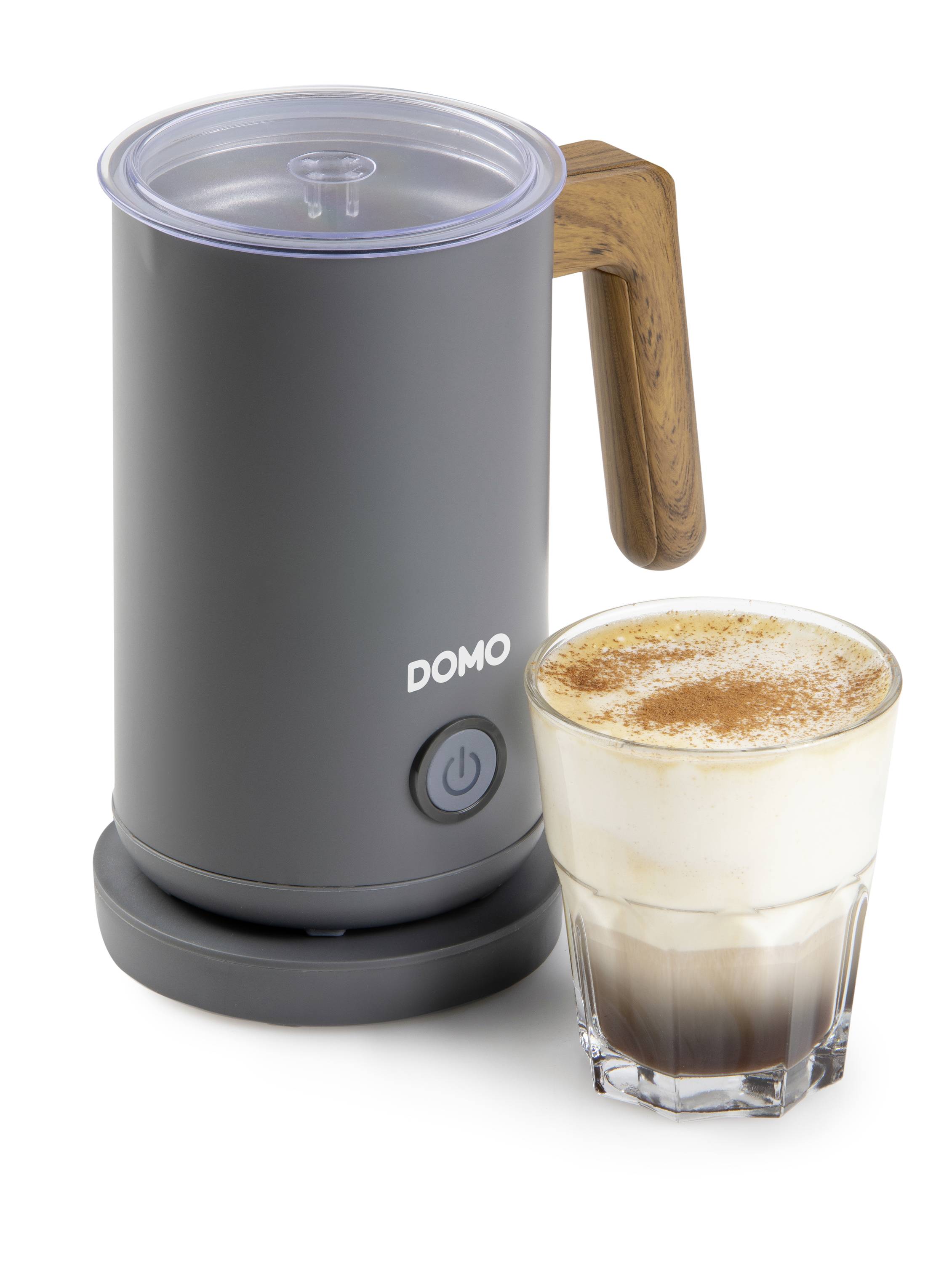 Ein elektrischer Milchaufschäumer neben einem Glas Latte Macchiato mit Milchschaum und Kakaopulver bestreut.