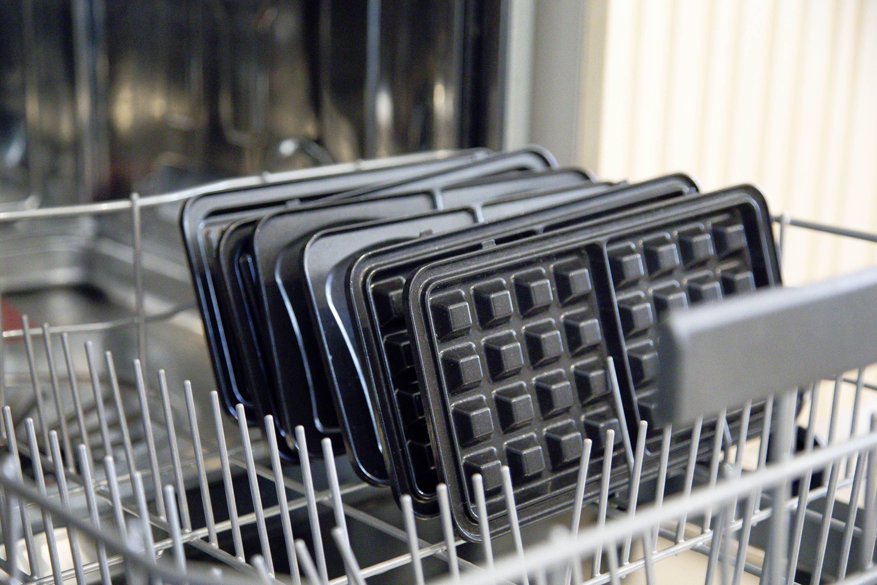 Waffeleisenplatten werden in einem Geschirrspüler gereinigt, mit den Platten aufrecht in einem oberen Gestell platziert.