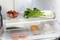Ein Kühlschrank mit Erdbeeren in einer Schale, frischem Pak Choi oben und Fisch und Hähnchen in der unteren Ablage.