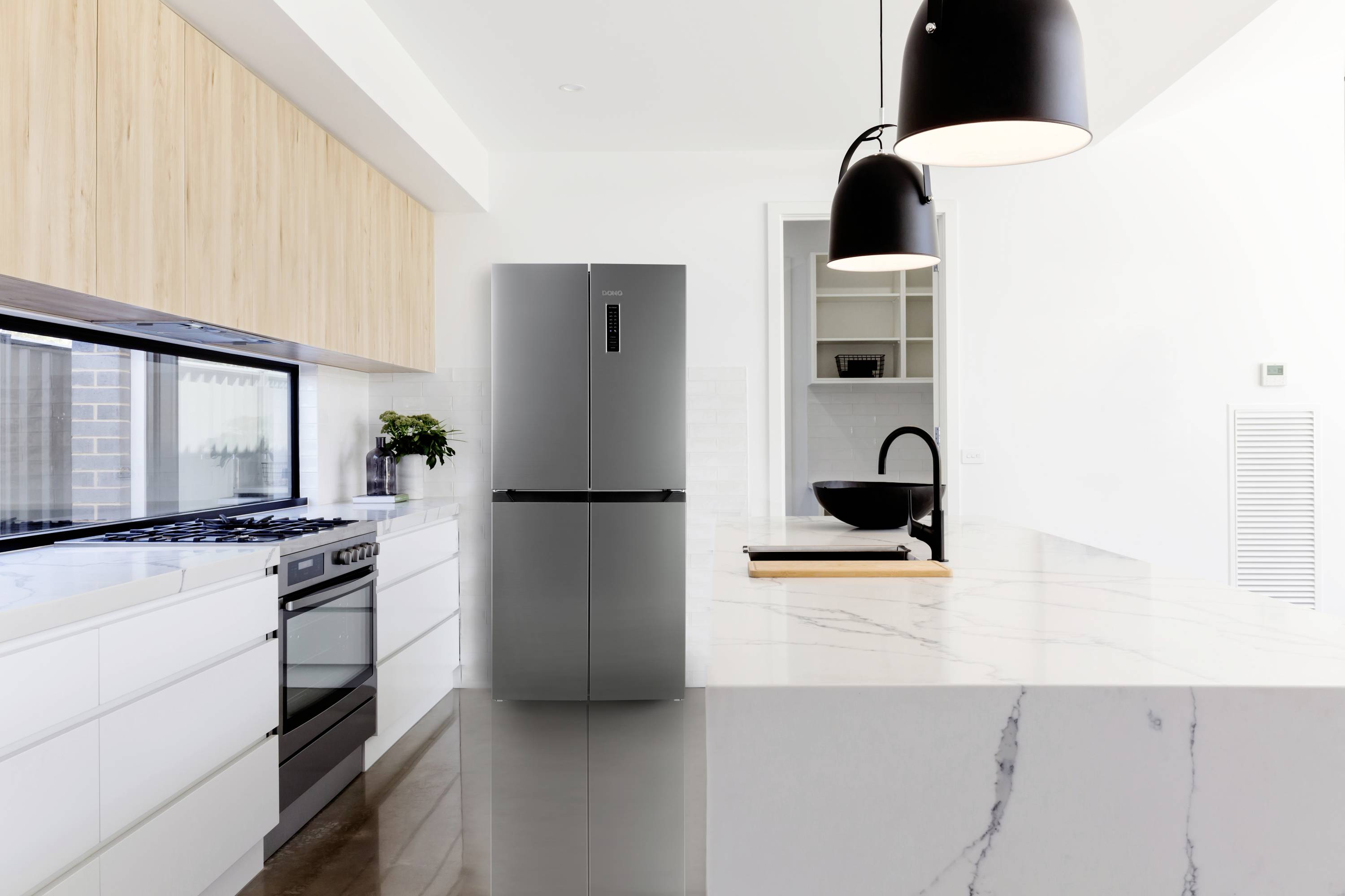Moderne Küche mit weißem Marmor und Holzdetails, schwarzer Ofen und Kühlschrank, zwei schwarze Hängeleuchten über der Theke.