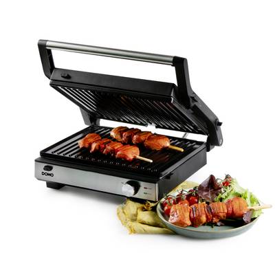 Ein Elektrogrill mit geöffnetem Deckel grillt zwei Fleischspieße. Daneben liegt ein Teller mit frischen Salatblättern und Tomaten.