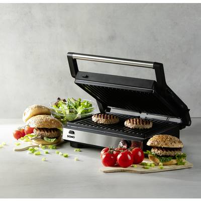 Ein offener Kontaktgrill mit zwei Burger-Patties darauf. Daneben liegen fertige Hamburger mit Salat und Tomaten als Beilagen.