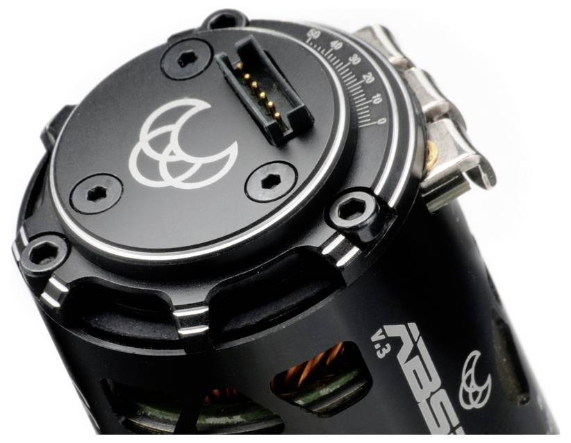 Ein schwarzes, zylindrisches Gerät mit silbernen Schrauben und einem Logo mit drei Monden. Der obere Bereich hat Skalenmarkierungen.