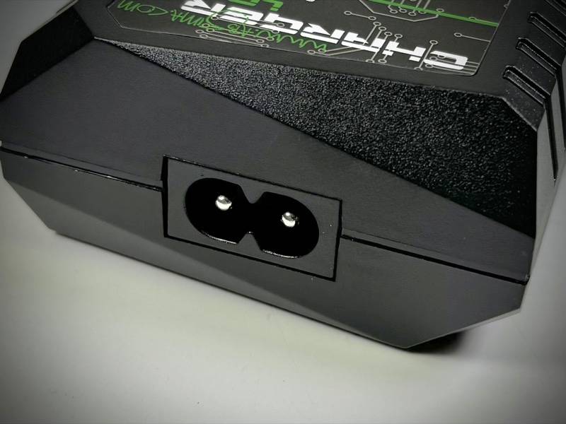 Schwarzes elektronisches Gerät mit zweipoligem Netzanschluss an der Vorderseite auf einem weißen Hintergrund.