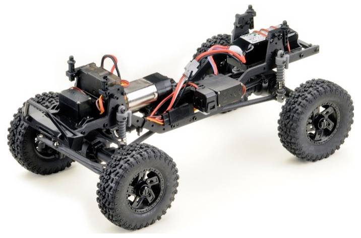 Ferngesteuertes Chassis eines Geländewagens mit freigelegten elektronischen Komponenten und dicken Offroad-Reifen, bereit für Montage.