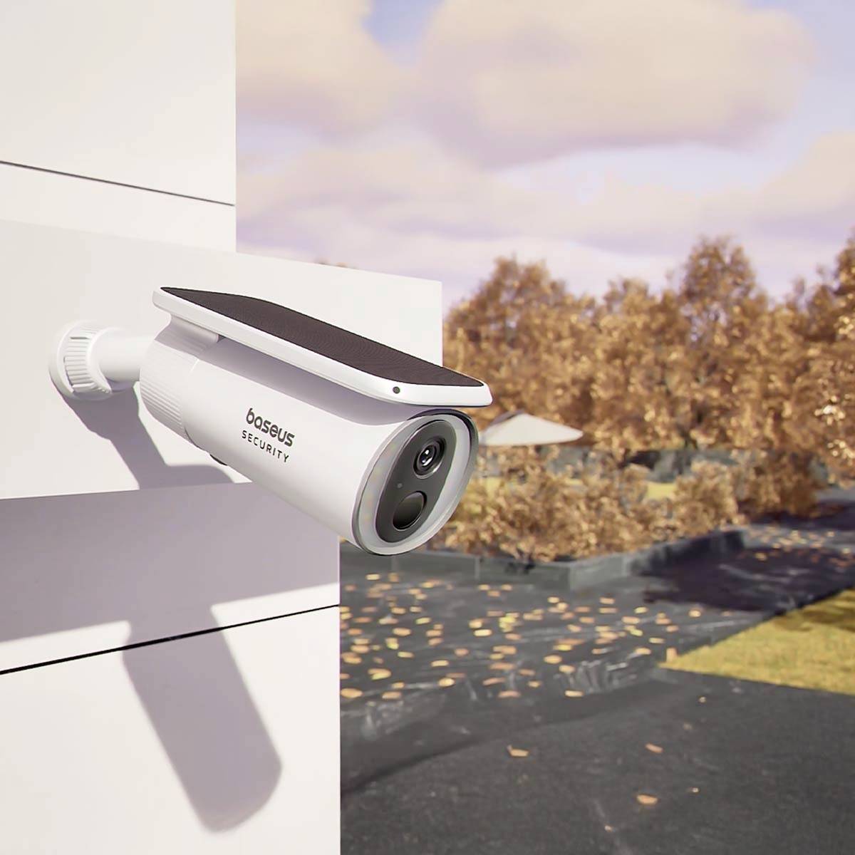 Überwachungskamera an weißer Wand montiert, blickt auf einen von Herbstbäumen gesäumten Weg.