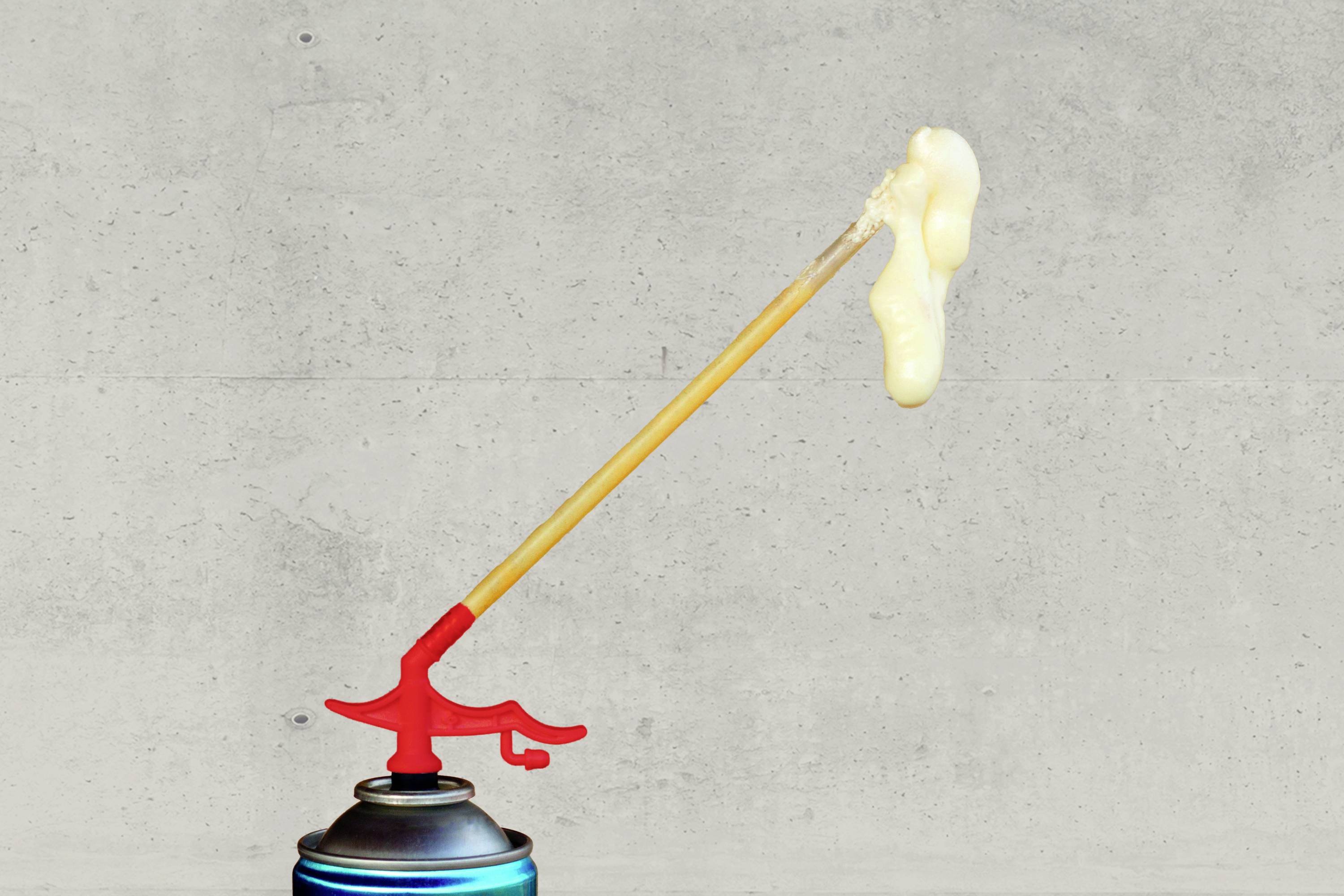 Eine Dose Bauschaum mit rotem Applikator, aus dem Schaum in einer langen, geschwungenen Form austritt. Hintergrund aus Beton.