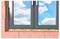 Eine 'gedämmte Wand mit Ziegeln und Schaum' zeigt einen Wandabschnitt mit roten Ziegeln und Dämmschaum um ein Fenster herum. Durch das Fenster ist blauer Himmel mit Wolken zu sehen.