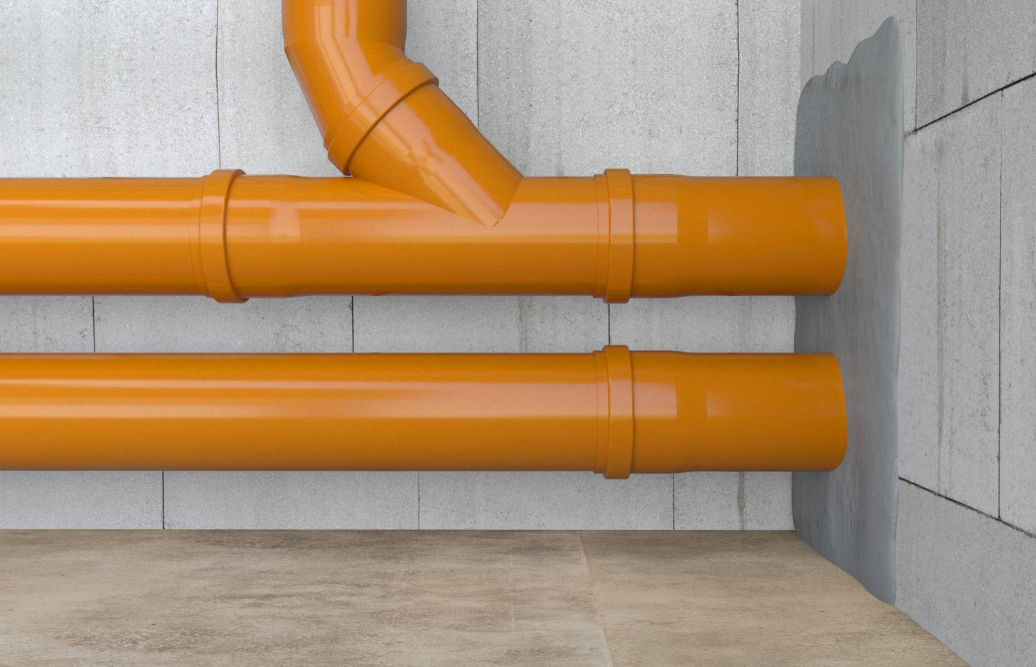 Orange Drainagerohre verlaufen horizontal entlang einer Betonwand, wobei sich ein Rohr in einem Winkel nach oben verzweigt.