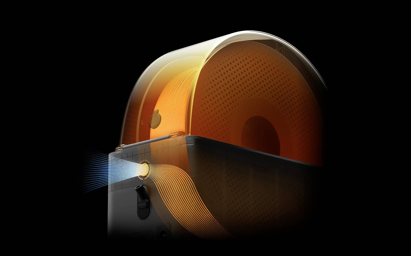 'Orange förmiges Objekt in dunkel beleuchtetem Raum, das von rechts strahlt. Moderne Technik, möglicherweise ein Ventilator oder Luftreiniger.'