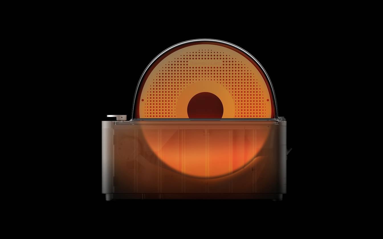 Ein rot beleuchteter, halbtransparenter Toaster auf schwarzem Hintergrund zeigt das Innere des Geräts mit kreisförmigem Heizelement.