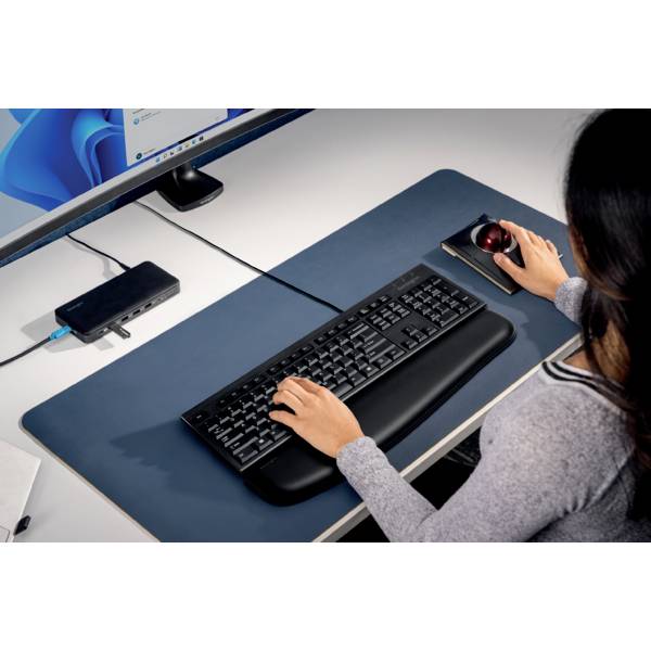 Eine Person arbeitet an einem Schreibtisch mit Computer, Tastatur und ergonomischer Maus. Auf dem Monitor ist Windows sichtbar.