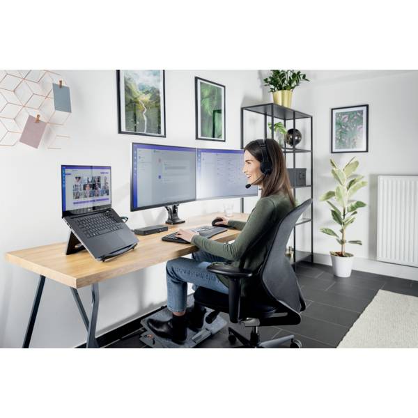 Eine Frau sitzt an einem Schreibtisch mit drei Monitoren, arbeitet am Computer und trägt ein Headset. Der Raum ist modern dekoriert.