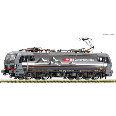 Eine schwarze Lokomotive der SBB Cargo International mit Bergmotiv auf der Seite, auf einem Gleis stehend. Oberleitung ist angehoben.