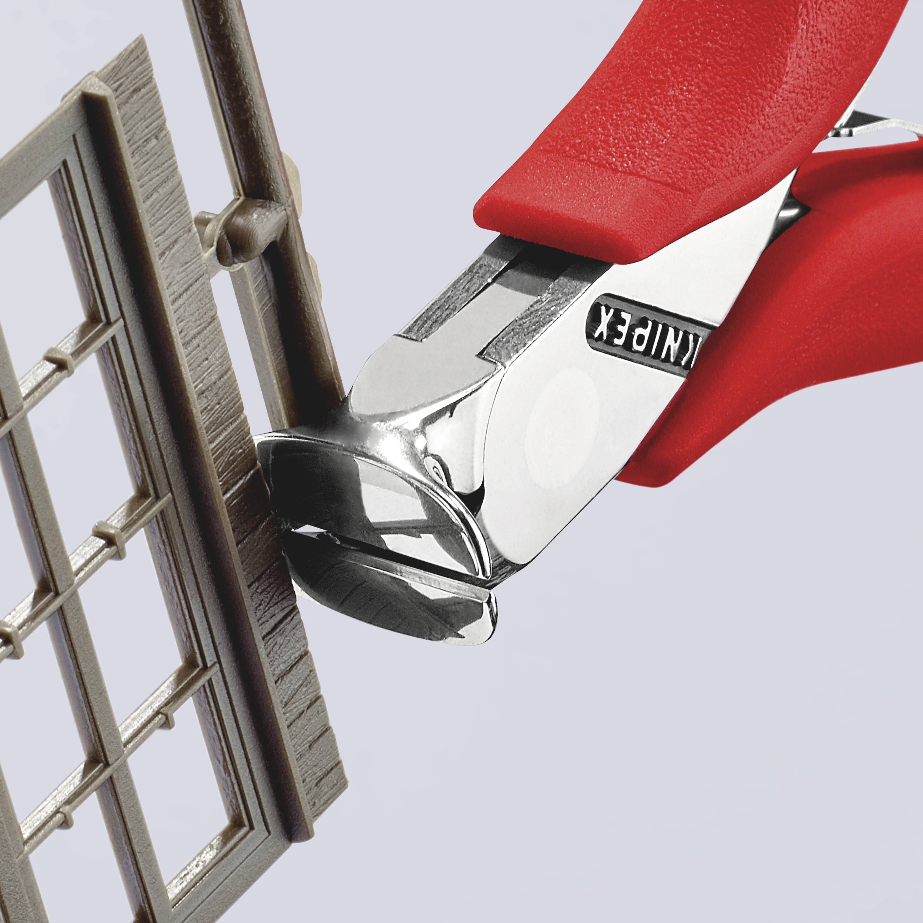 Ein roter Seitenschneider durchtrennt präzise den Rahmen eines kleinen Modellfensters.