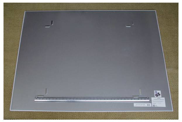 Eine große graue Metallplatte mit Haken und einem Lineal daran befestigt, liegt auf einer braunen Oberfläche.