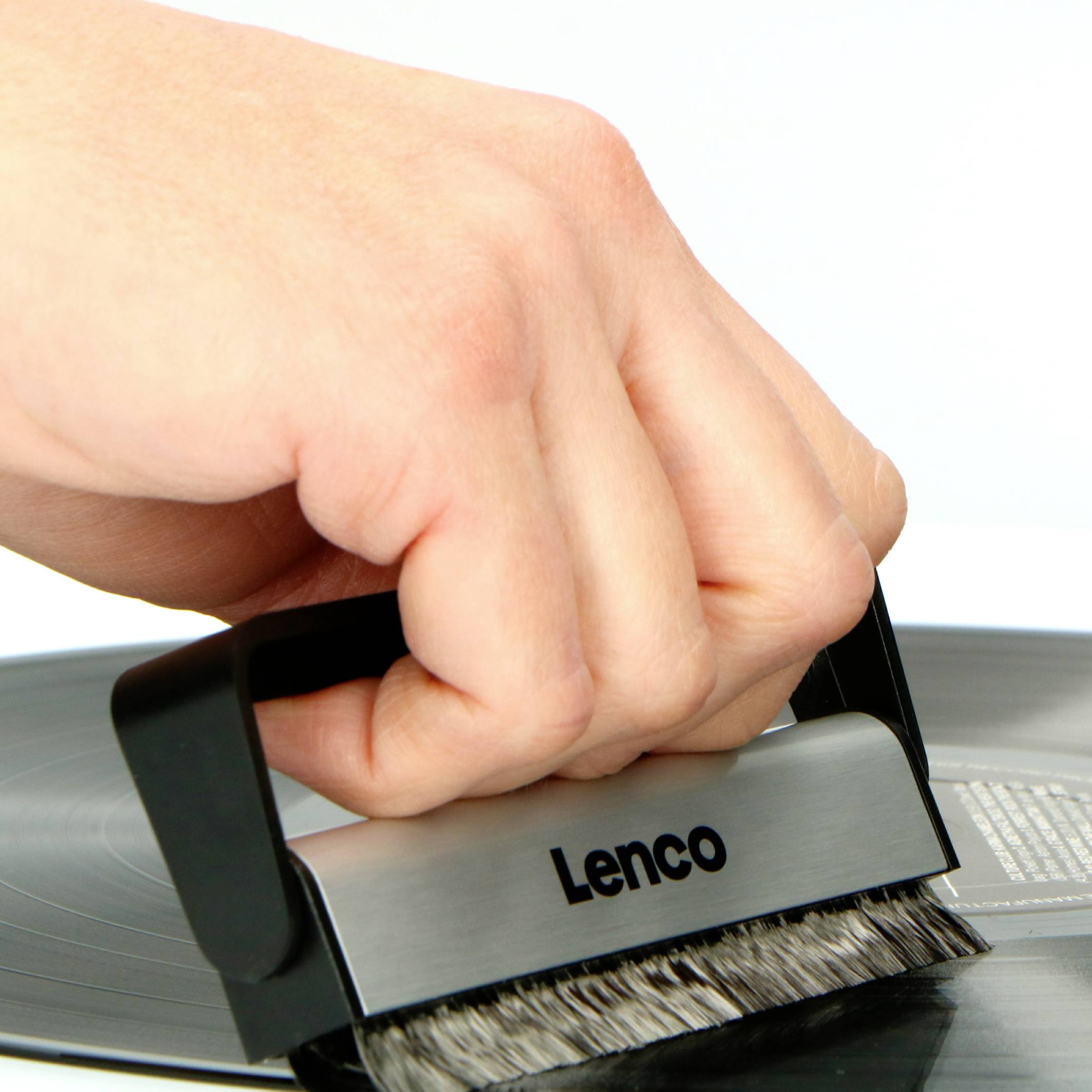 Hand reinigt eine Schallplatte mit einer Bürste von Lenco.