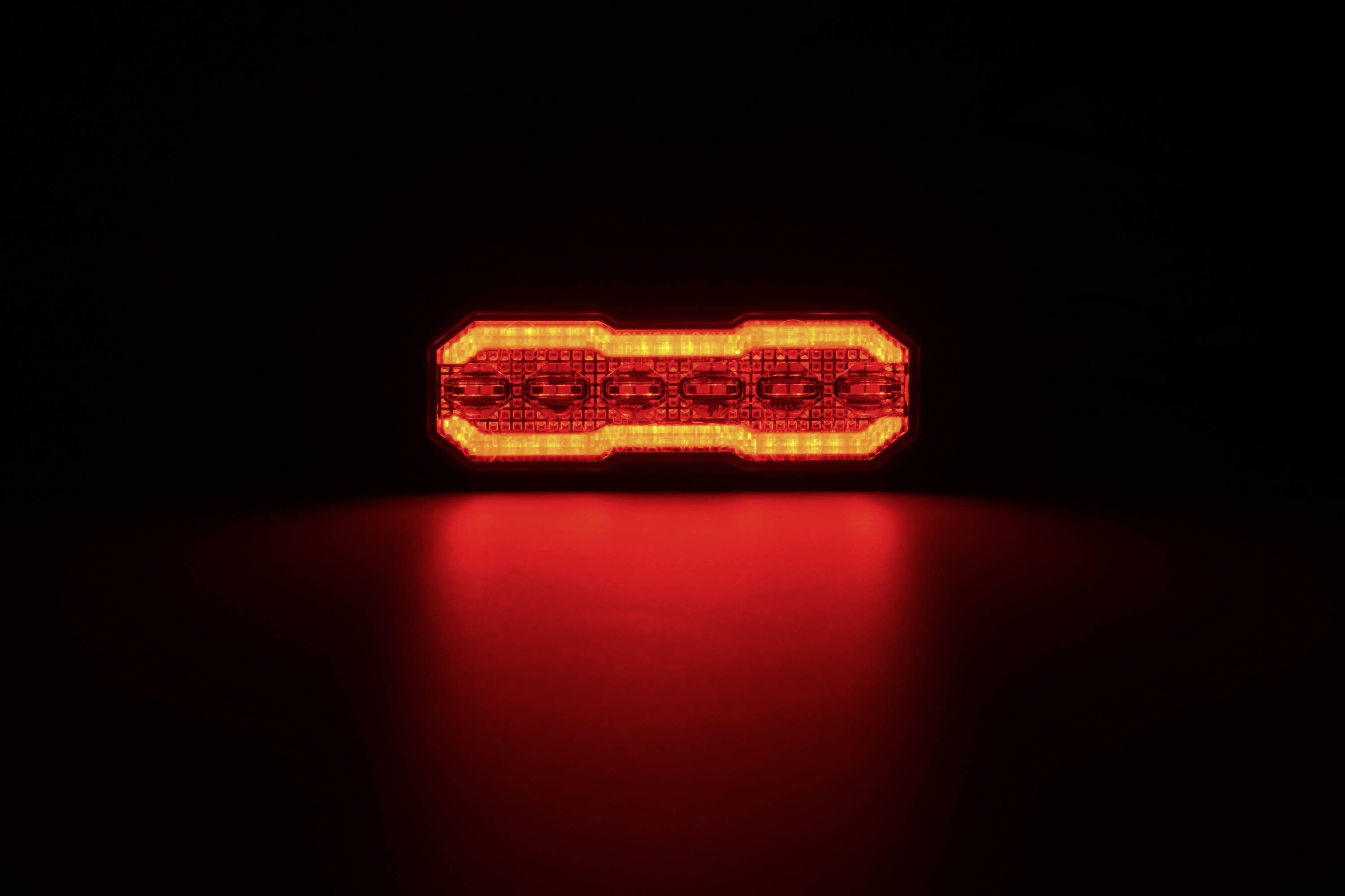 Eine helle rote LED-Fahrradlampe leuchtete in der Dunkelheit und warf einen rötlichen Schein auf die Oberfläche darunter.