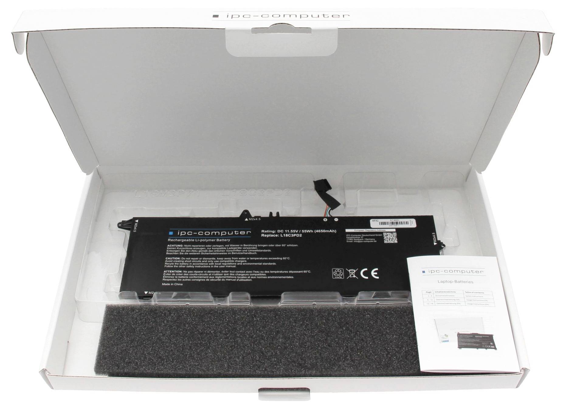 Eine schwarze Laptop-Batterie liegt in einer offenen weißen Verpackung. Daneben befindet sich ein Benutzerhandbuch.