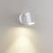 Wandleuchte in zylindrischer Form aus weißem Metall, leuchtet nach unten und beleuchtet die beige Wand in sanftem Licht.