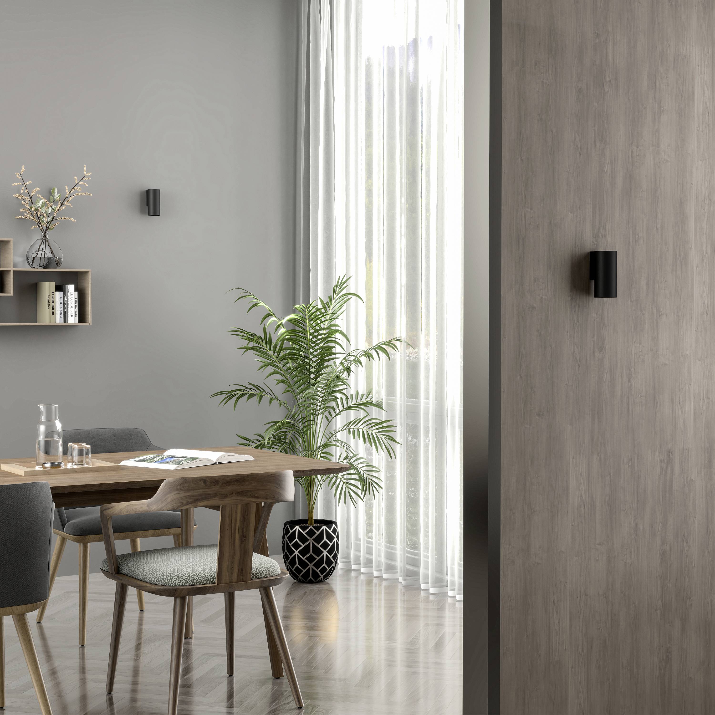 Esszimmer mit Holztisch und Stühlen neben einem großen Fenster. Eine Pflanze in der Ecke und Regale mit Dekoration an der Wand.