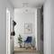 Moderner Flur mit Holzfußboden, blauer Stuhl, Galerie-Bild an der Wand, Pflanze und Garderobe mit Hüten. Schlichter, eleganter Stil.