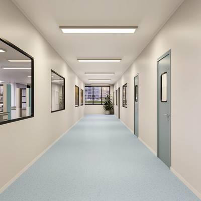 Ein leerer Krankenhausflur mit hellblauem Boden und Türen auf beiden Seiten; große Fenster am Ende lassen Tageslicht herein.