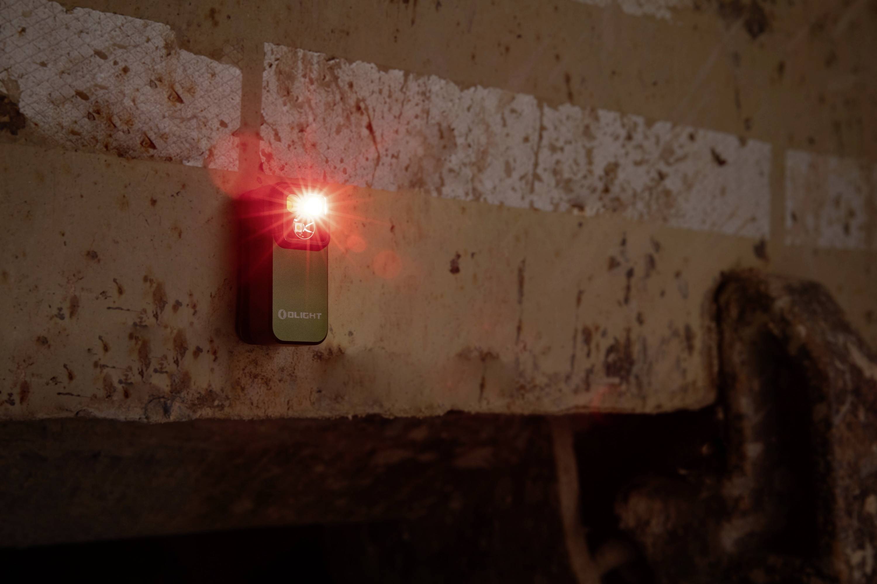 Ein kleines, rotes, blinkendes Licht an einer rostigen Metalloberfläche, vermutlich zur Kennzeichnung oder Warnung montiert.