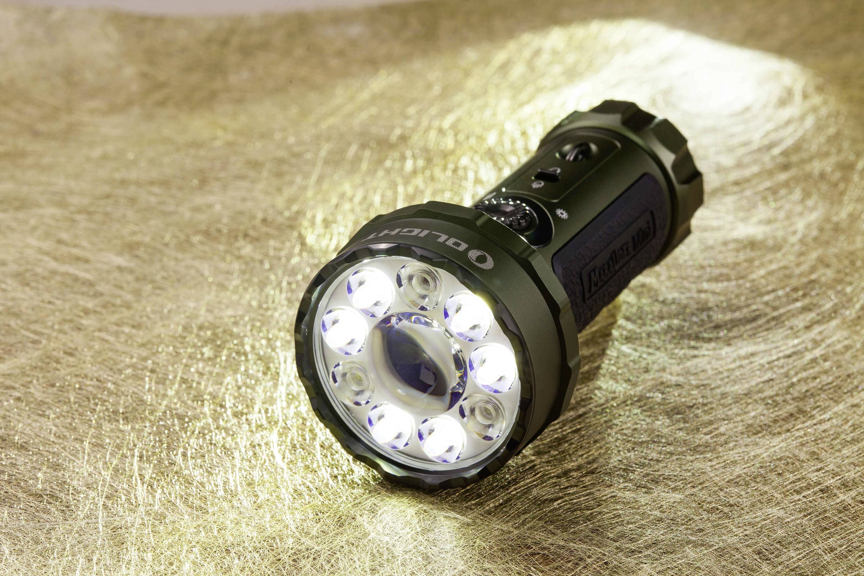 Eine robuste Taschenlampe mit mehreren leuchtenden LEDs liegt auf einer schimmernden, goldenen Oberfläche.