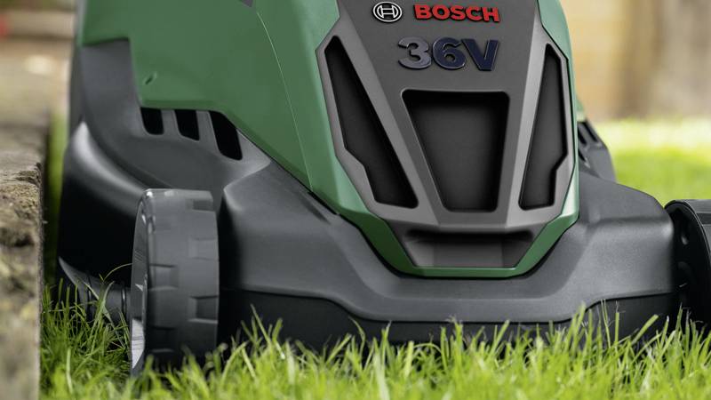 Ein Akku-Rasenmäher mit der Aufschrift 'Bosch 36V', steht auf grünem Gras, bereit zum Einsatz im Garten.