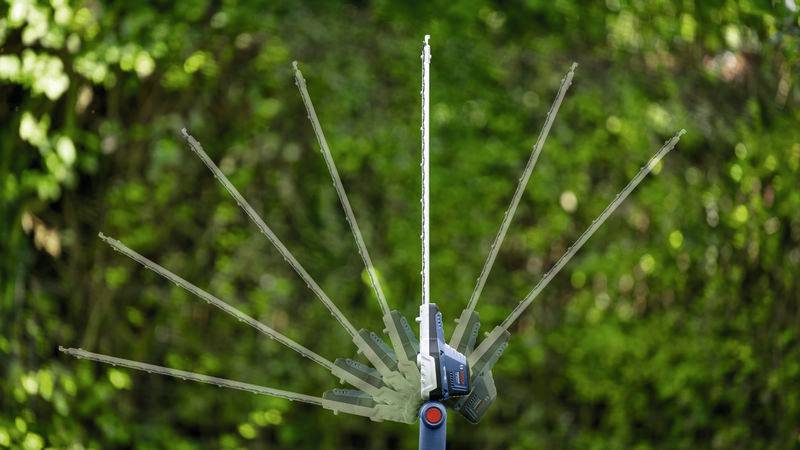 Heckenschere bewegt sich halbkreisförmig vor grünem Hintergrund.